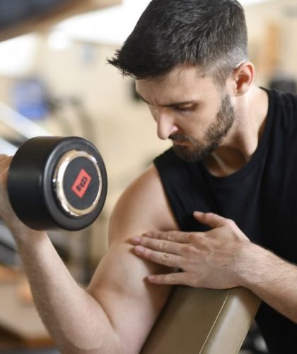 Focused man lifting dumbbell, showcasing strength and fitness indoors.