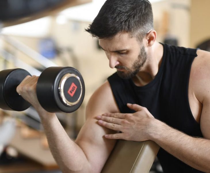 Focused man lifting dumbbell, showcasing strength and fitness indoors.